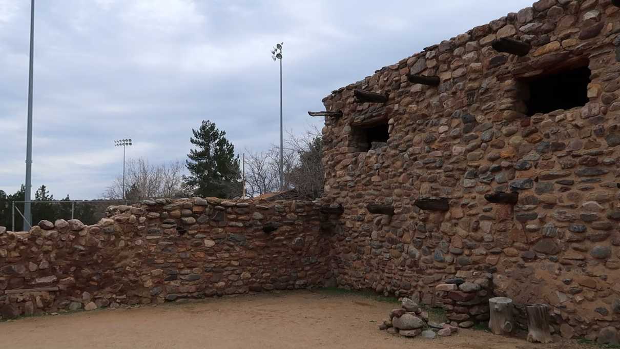 Stone wall and building in foreground with flood lights in background